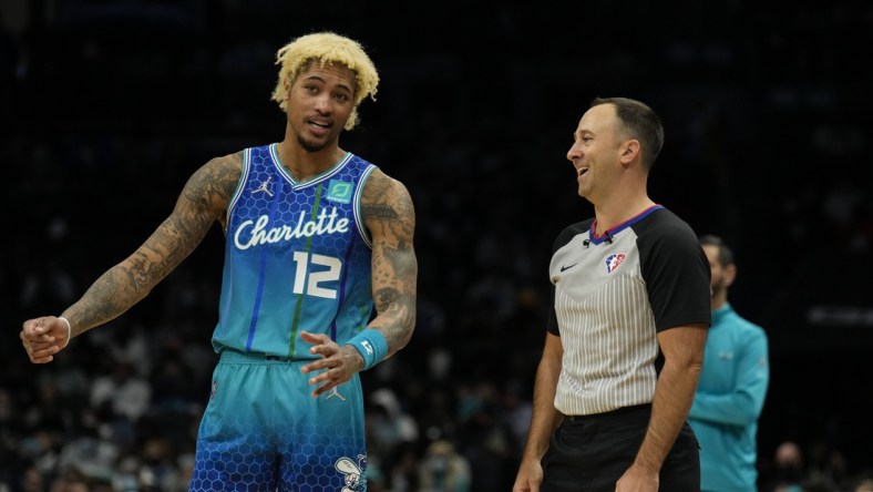 Jan 8, 2022; Charlotte, North Carolina, USA; Charlotte Hornets guard Kelly Oubre Jr. (12) talks with official Kane Fitzgerald (5) during the second half against the Milwaukee Bucks at the Spectrum Center. Mandatory Credit: Jim Dedmon-USA TODAY Sports