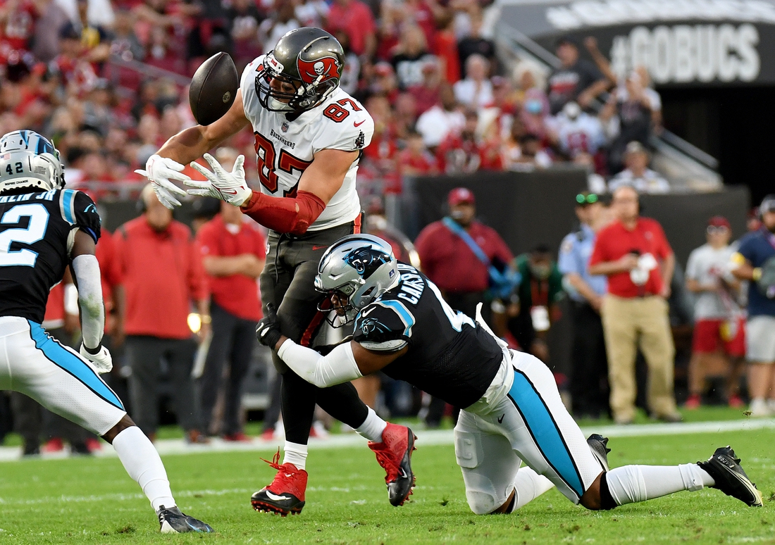 Jan 9, 2022; Tampa, Florida, USA;  Tampa Bay Buccaneers tight end Rob Gronkowski (87) juggles the ball as Carolina Panthers linebacker Jermaine Carter Jr. (4) attempts to make the tackle  in the first half at Raymond James Stadium. Mandatory Credit: Jonathan Dyer-USA TODAY Sports