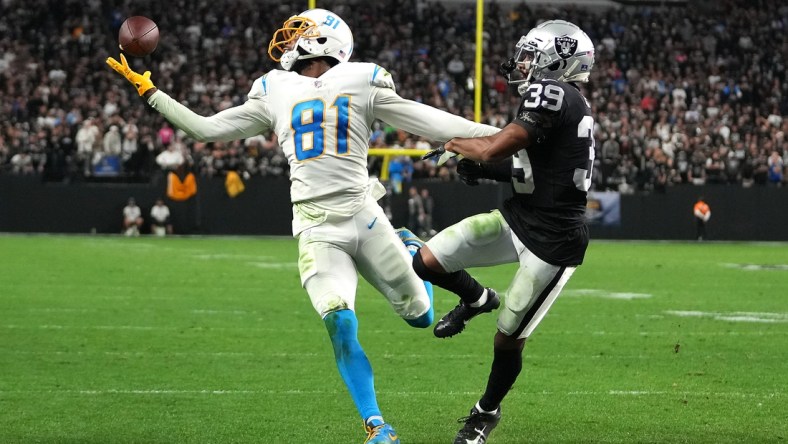 Jan 9, 2022; Paradise, Nevada, USA; Los Angeles Chargers wide receiver Mike Williams (81) reaches for a pass as Las Vegas Raiders cornerback Nate Hobbs (39) defends during an overtime period at Allegiant Stadium. Mandatory Credit: Stephen R. Sylvanie-USA TODAY Sports