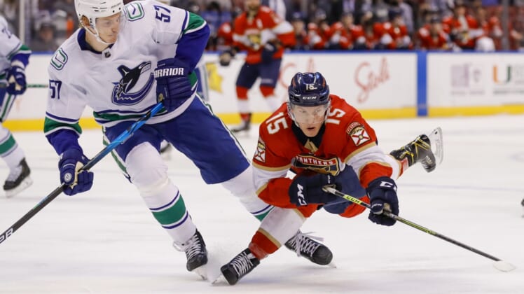 Jan 11, 2022; Sunrise, Florida, USA; Florida Panthers center Anton Lundell (15) dives for the puck against Vancouver Canucks defenseman Tyler Myers (57) during the first period at FLA Live Arena. Mandatory Credit: Sam Navarro-USA TODAY Sports