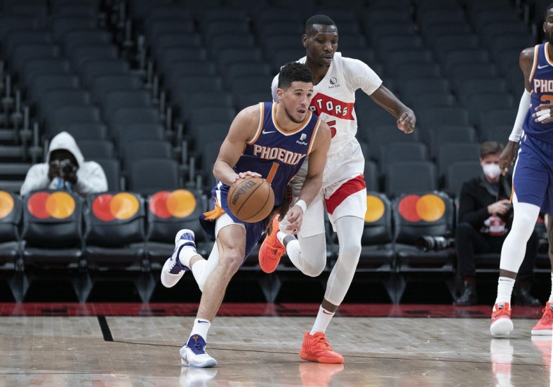 Jan 11, 2022; Toronto, Ontario, CAN; Phoenix Suns guard Devin Booker (1) dribbles the ball as Toronto Raptors forward Chris Boucher (25) defends during the fourth quarter at Scotiabank Arena. Mandatory Credit: Nick Turchiaro-USA TODAY Sports