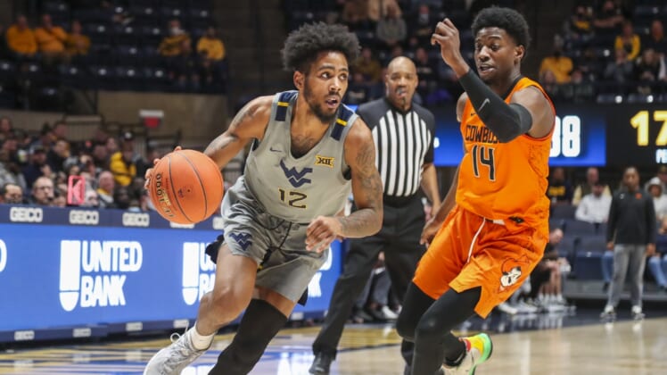Jan 11, 2022; Morgantown, West Virginia, USA; West Virginia Mountaineers guard Taz Sherman (12) drives past Oklahoma State Cowboys guard Bryce Williams (14) during the second half at WVU Coliseum. Mandatory Credit: Ben Queen-USA TODAY Sports