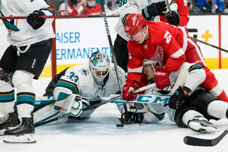 Jan 11, 2022; San Jose, California, USA; San Jose Sharks goaltender Adin Hill (33) reaches for the puck after a collision with Detroit Red Wings left wing Lucas Raymond (23) during the first period at SAP Center at San Jose. Mandatory Credit: John Hefti-USA TODAY Sports