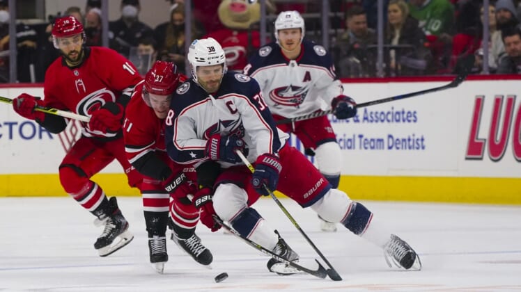 Jan 13, 2022; Raleigh, North Carolina, USA; Columbus Blue Jackets center Boone Jenner (38) handles the puck against Carolina Hurricanes right wing Andrei Svechnikov (37) during the first period at PNC Arena. Mandatory Credit: James Guillory-USA TODAY Sports