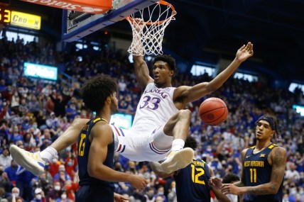 Kansas senior forward David McCormack (33) hangs on the rim after dunking over West Virginia during the second half of Saturday's game inside Allen Fieldhouse.