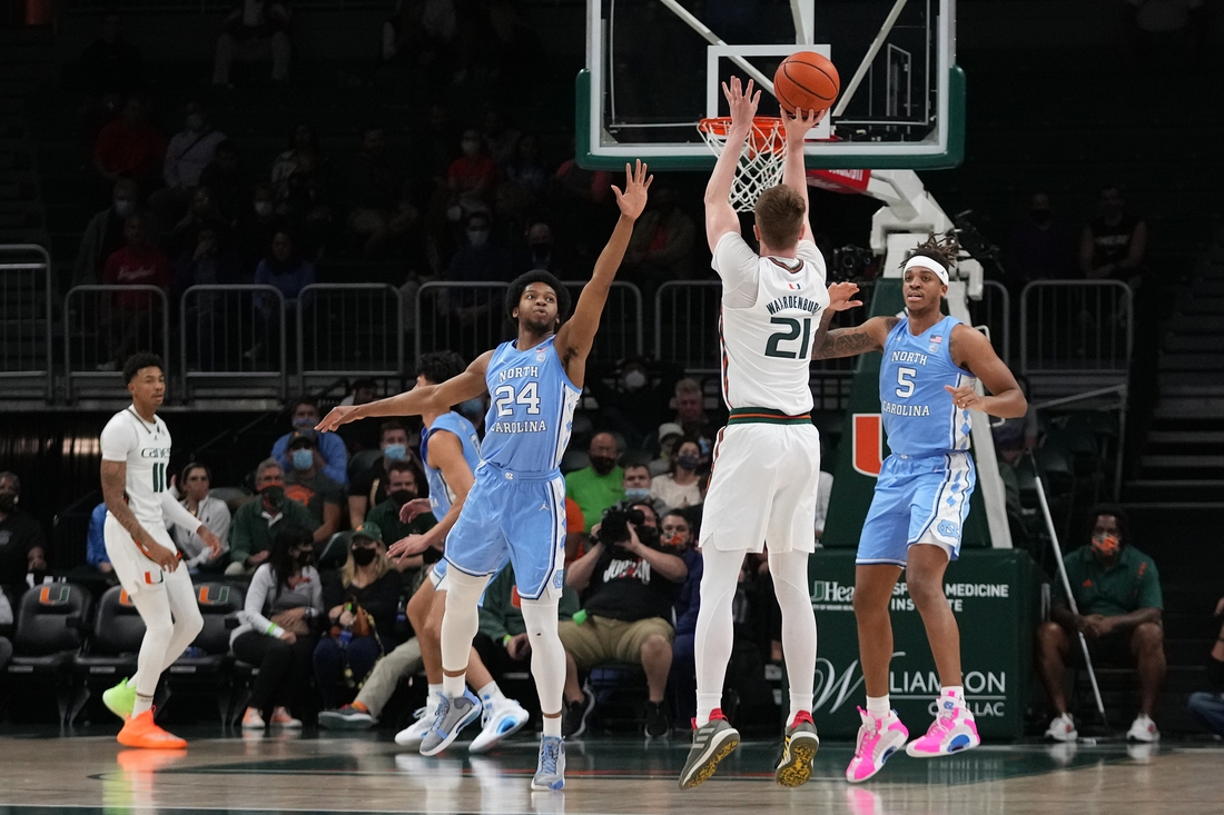 Jan 18, 2022; Coral Gables, Florida, USA; Miami Hurricanes forward Sam Waardenburg (21) attempts a three point shot over North Carolina Tar Heels guard Kerwin Walton (24) during the first half at Watsco Center. Mandatory Credit: Jasen Vinlove-USA TODAY Sports