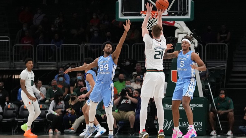 Jan 18, 2022; Coral Gables, Florida, USA; Miami Hurricanes forward Sam Waardenburg (21) attempts a three point shot over North Carolina Tar Heels guard Kerwin Walton (24) during the first half at Watsco Center. Mandatory Credit: Jasen Vinlove-USA TODAY Sports