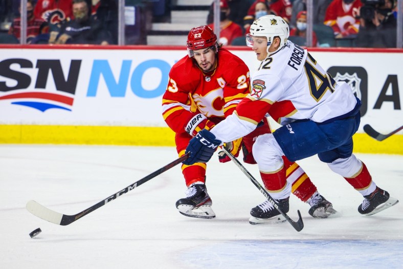 Jan 18, 2022; Calgary, Alberta, CAN; Florida Panthers defenseman Gustav Forsling (42) and Calgary Flames center Sean Monahan (23) battle for the puck during the first period at Scotiabank Saddledome. Mandatory Credit: Sergei Belski-USA TODAY Sports