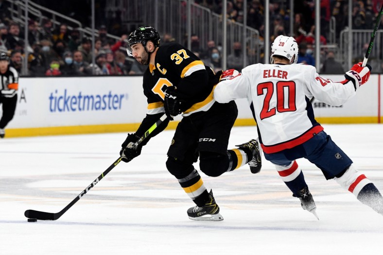 Jan 20, 2022; Boston, Massachusetts, USA; Boston Bruins center Patrice Bergeron (37) skates with the puck across the blue line in front of Washington Capitals center Lars Eller (20) during the first period at the TD Garden. Mandatory Credit: Brian Fluharty-USA TODAY Sports
