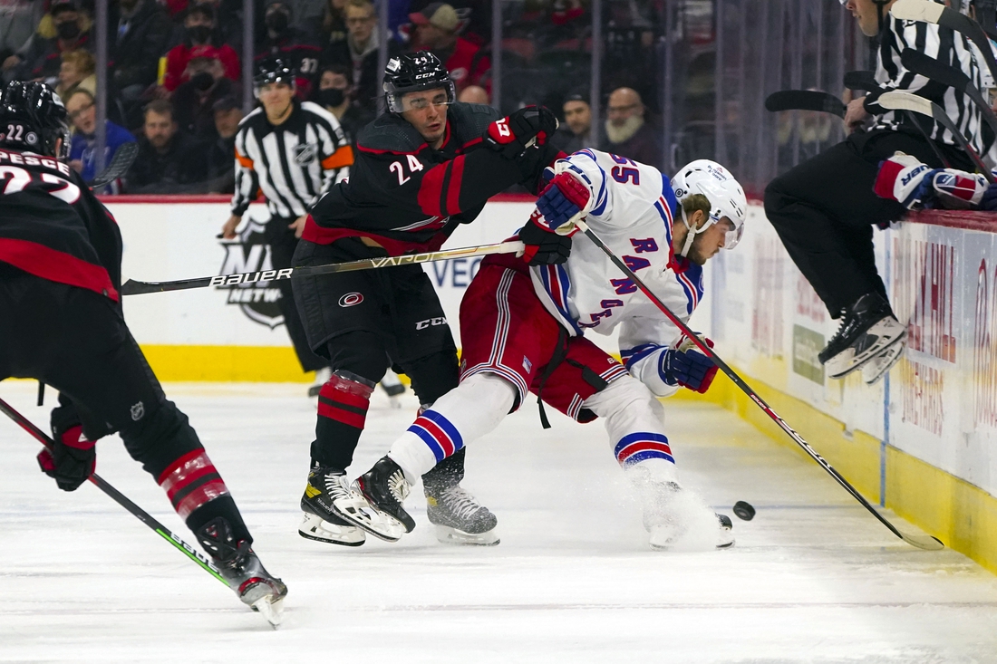 Jan 21, 2022; Raleigh, North Carolina, USA;  Carolina Hurricanes center Seth Jarvis (24) checks New York Rangers defenseman Ryan Lindgren (55) during the first period at PNC Arena. Mandatory Credit: James Guillory-USA TODAY Sports