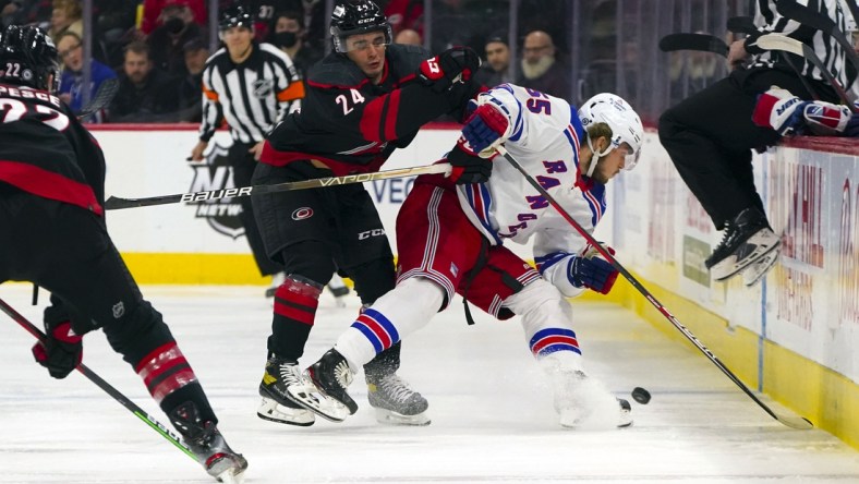 Jan 21, 2022; Raleigh, North Carolina, USA;  Carolina Hurricanes center Seth Jarvis (24) checks New York Rangers defenseman Ryan Lindgren (55) during the first period at PNC Arena. Mandatory Credit: James Guillory-USA TODAY Sports