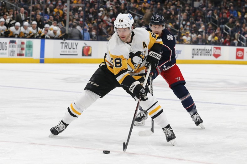 Jan 21, 2022; Columbus, Ohio, USA; Pittsburgh Penguins defenseman Kris Letang (58) passes the puck as Columbus Blue Jackets center Sean Kuraly (7) trails the play during the first period at Nationwide Arena. Mandatory Credit: Russell LaBounty-USA TODAY Sports