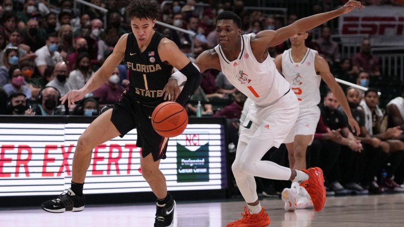 Jan 22, 2022; Coral Gables, Florida, USA; Florida State Seminoles guard Jalen Warley (1) and Miami Hurricanes forward Anthony Walker (1) chase a loose ball during the first half at Watsco Center. Mandatory Credit: Jasen Vinlove-USA TODAY Sports