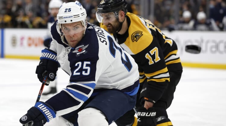 Jan 22, 2022; Boston, Massachusetts, USA; Winnipeg Jets center Paul Stastny (25) eyes a loose puck as Boston Bruins left wing Nick Foligno (17) skates by during the second period at TD Garden. Mandatory Credit: Winslow Townson-USA TODAY Sports