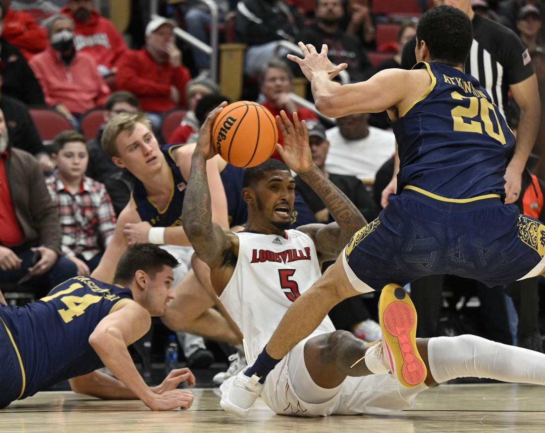 Jan 22, 2022; Louisville, Kentucky, USA;  Louisville Cardinals forward Malik Williams (5) looks to pass the ball during a scramble with Notre Dame Fighting Irish forward Nate Laszewski (14) and forward Paul Atkinson Jr. (20) during the second half at KFC Yum! Center. Notre Dame defeated Louisville 82-70. Mandatory Credit: Jamie Rhodes-USA TODAY Sports