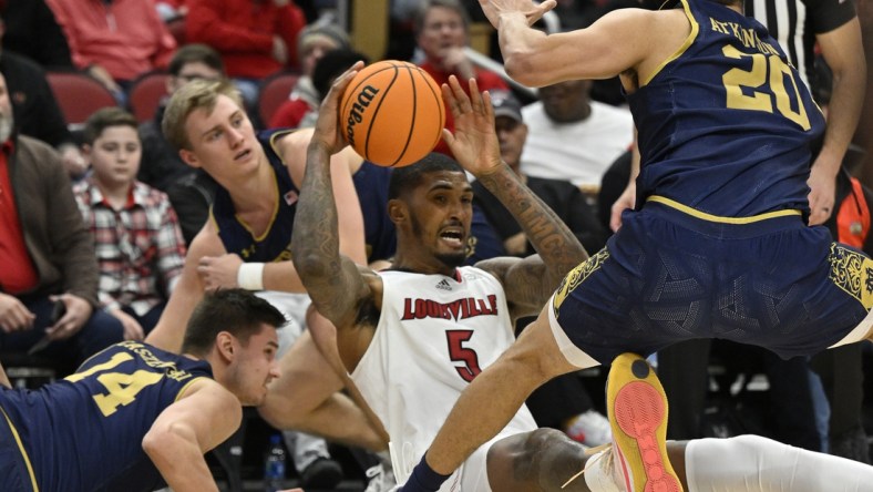 Jan 22, 2022; Louisville, Kentucky, USA;  Louisville Cardinals forward Malik Williams (5) looks to pass the ball during a scramble with Notre Dame Fighting Irish forward Nate Laszewski (14) and forward Paul Atkinson Jr. (20) during the second half at KFC Yum! Center. Notre Dame defeated Louisville 82-70. Mandatory Credit: Jamie Rhodes-USA TODAY Sports