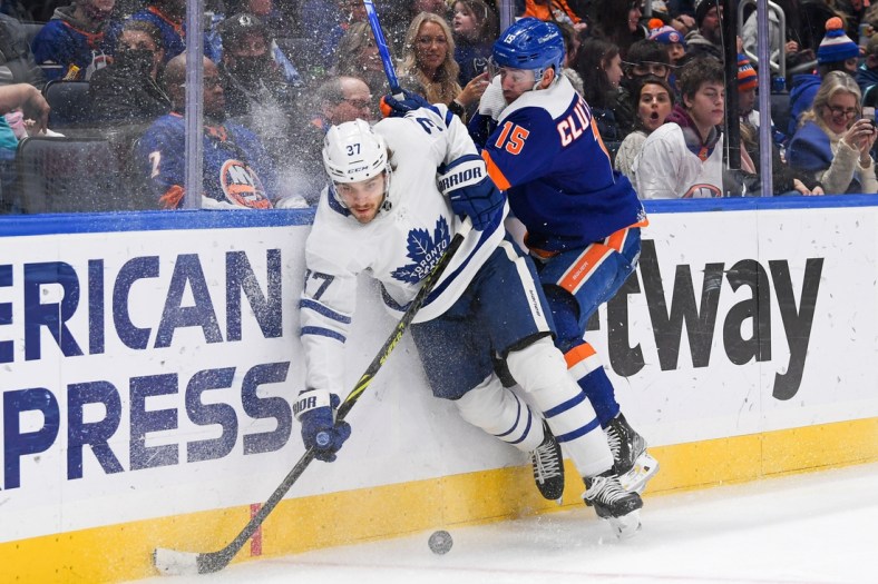 Jan 22, 2022; Elmont, New York, USA;  New York Islanders right wing Cal Clutterbuck (15) checks Toronto Maple Leafs defenseman Timothy Liljegren (37) into the boards during the second period at UBS Arena. Mandatory Credit: Dennis Schneidler-USA TODAY Sports