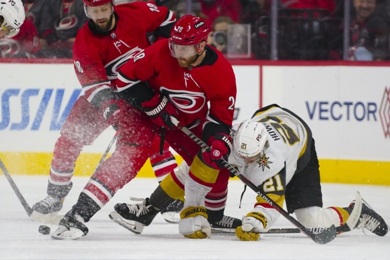 Jan 25, 2022; Raleigh, North Carolina, USA;  Carolina Hurricanes defenseman Ian Cole (28) battles over the puck against Vegas Golden Knights center Brett Howden (21) during the first period at PNC Arena. Mandatory Credit: James Guillory-USA TODAY Sports