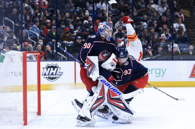 Jan 26, 2022; Columbus, Ohio, USA;  Columbus Blue Jackets goaltender Elvis Merzlikins (90) defends the net as right wing Jakub Voracek (93) collides with Calgary Flames center Sean Monahan (23) in the first period at Nationwide Arena. Mandatory Credit: Aaron Doster-USA TODAY Sports