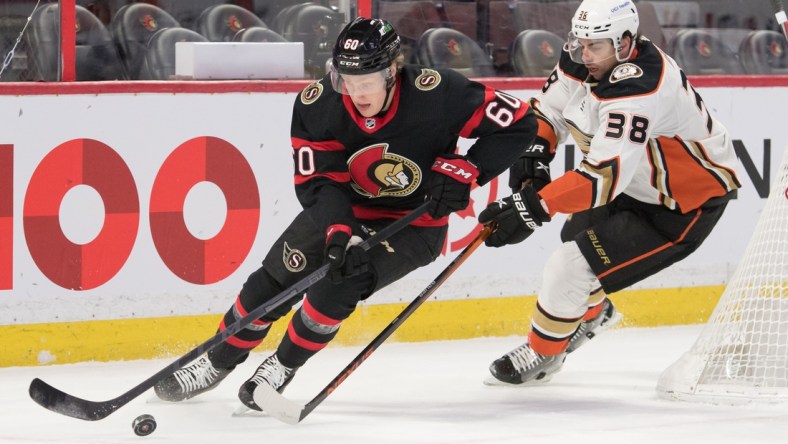 Jan 29, 2022; Ottawa, Ontario, CAN; Ottawa Senators defenseman Lassi Thomson (60) skates with the puck in front of Anaheim Ducks center Derek Grant (38) in the first period at the Canadian Tire Centre. Mandatory Credit: Marc DesRosiers-USA TODAY Sports