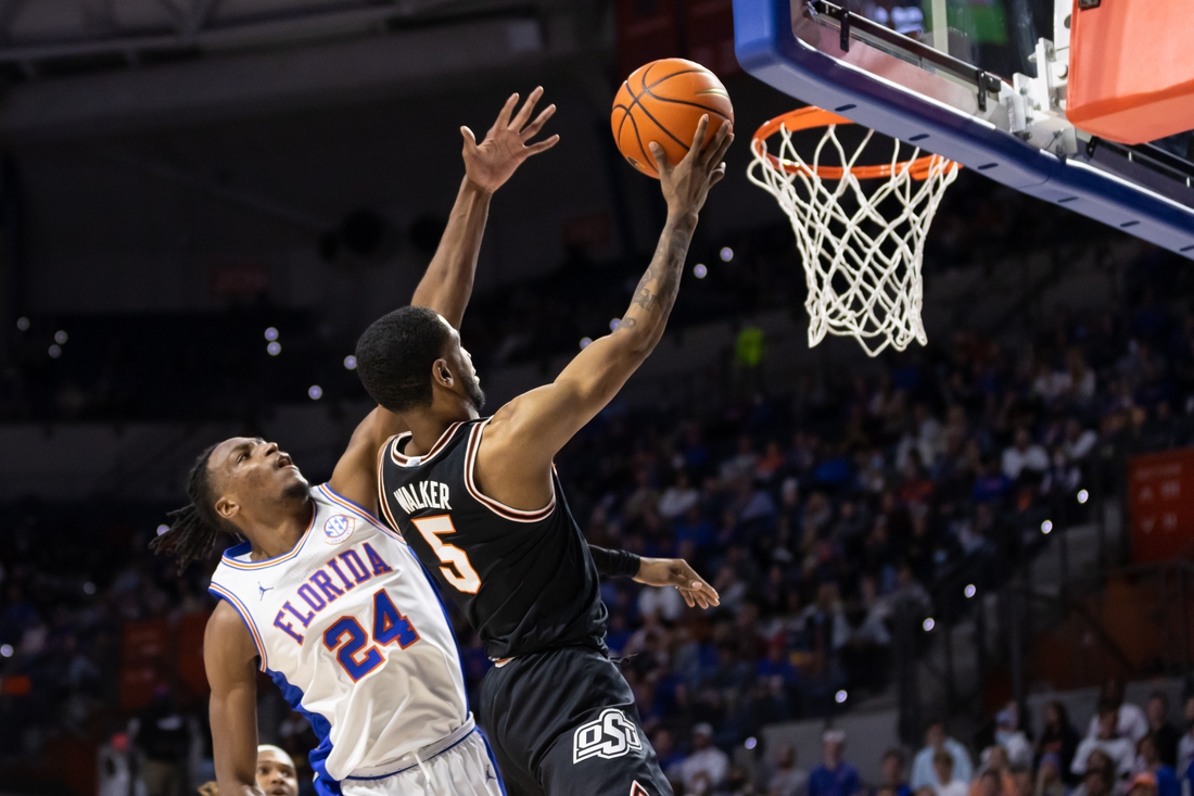 Jan 29, 2022; Gainesville, Florida, USA; Oklahoma State Cowboys guard Rondel Walker (5) makes a layup over Florida Gators guard Phlandrous Fleming Jr. (24) during the first half at Billy Donovan Court at Exactech Arena. Mandatory Credit: Matt Pendleton-USA TODAY Sports