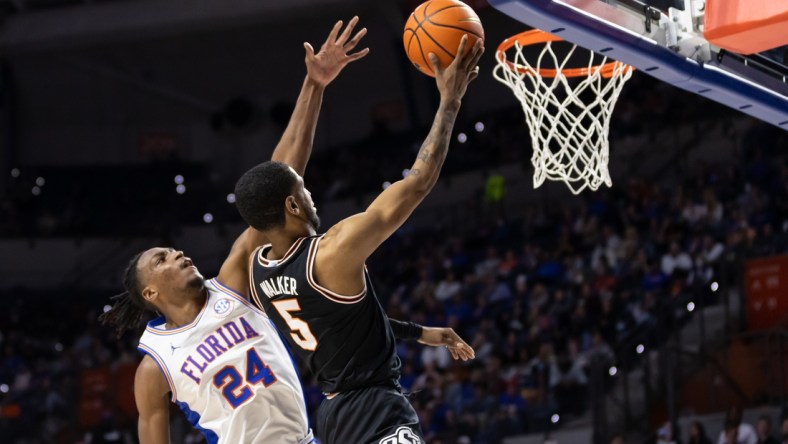 Jan 29, 2022; Gainesville, Florida, USA; Oklahoma State Cowboys guard Rondel Walker (5) makes a layup over Florida Gators guard Phlandrous Fleming Jr. (24) during the first half at Billy Donovan Court at Exactech Arena. Mandatory Credit: Matt Pendleton-USA TODAY Sports