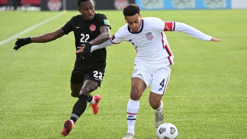 Jan 30, 2022; Hamilton, Ontario, CAN;   Canada defender Richie Laryea (22) battles for the ball with United States midfielder Tyler Adams (4) during a CONCACAF FIFA World Cup Qualifier soccer match at Tim Hortons Field. Mandatory Credit: Dan Hamilton-USA TODAY Sports