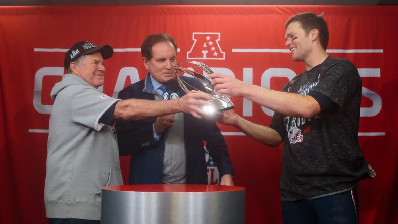 Jan 20, 2019; Kansas City, MO, USA; CBS sportscaster Jim Nantz (center) looks on as New England Patriots head coach Bill Belichick hands the trophy to quarterback Tom Brady (12) after their win over the Kansas City Chiefs in the AFC Championship game at Arrowhead Stadium. Mandatory Credit: Mark J. Rebilas-USA TODAY Sports