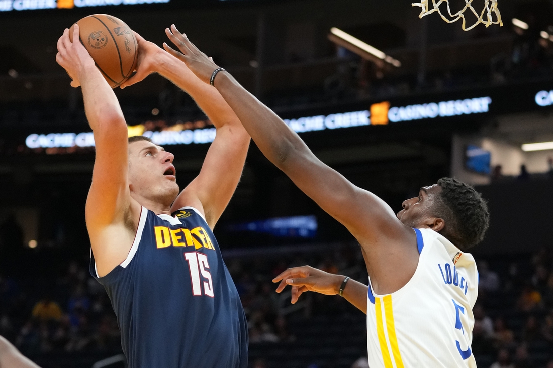 October 6, 2021; San Francisco, California, USA; Denver Nuggets center Nikola Jokic (15) shoots the basketball against Golden State Warriors center Kevon Looney (5) during the first quarter at Chase Center. Mandatory Credit: Kyle Terada-USA TODAY Sports