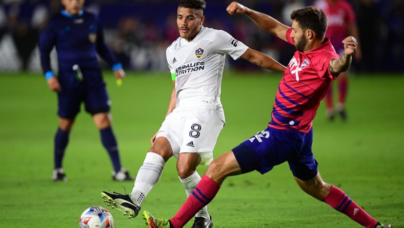 Oct 23, 2021; Carson, California, USA; Los Angeles Galaxy midfielder Jonathan dos Santos (8) moves the ball against FC Dallas midfielder Ryan Hollingshead (12) during the first half at StubHub Center. Mandatory Credit: Gary A. Vasquez-USA TODAY Sports