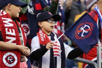 Nov 7, 2021; Foxborough, Massachusetts, USA; A young New England Revolution fan waves a flag with the team   s new logo for the 2022-23 season during the first half of the game between the New England Revolution and the Inter Miami at Gillette Stadium. Mandatory Credit: Winslow Townson-USA TODAY Sports