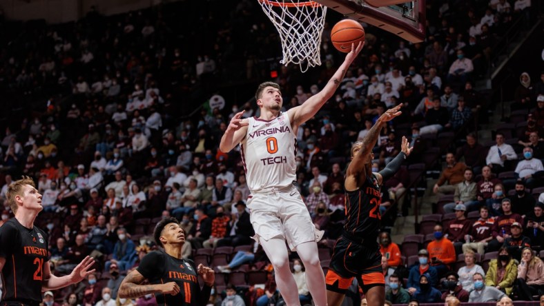 Jan 26, 2022; Blacksburg, Virginia, USA; Virginia Tech Hokies guard Hunter Cattoor (0) shoots over Miami Hurricanes guard Cameron McGusty (23) during the first half at Cassell Coliseum. Mandatory Credit: Ryan Hunt-USA TODAY Sports