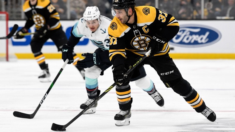 Feb 1, 2022; Boston, Massachusetts, USA; Boston Bruins center Patrice Bergeron (37) skates with the puck in front of Seattle Kraken center Yanni Gourde (37) during the first period at the TD Garden. Mandatory Credit: Brian Fluharty-USA TODAY Sports