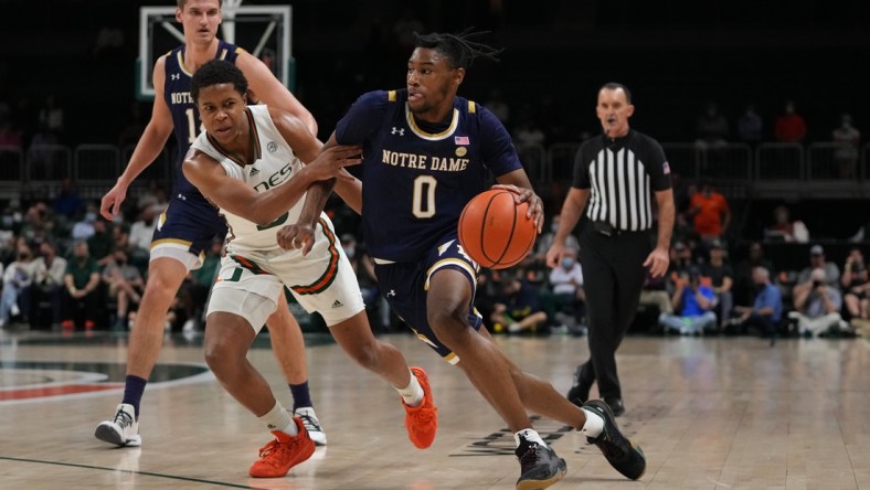 Feb 2, 2022; Coral Gables, Florida, USA; Notre Dame Fighting Irish guard Blake Wesley (0) drives the ball around Miami Hurricanes guard Charlie Moore (3) during the first half at Watsco Center. Mandatory Credit: Jasen Vinlove-USA TODAY Sports