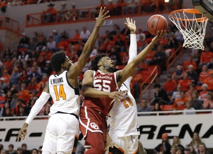 Feb 5, 2022; Stillwater, Oklahoma, USA; Oklahoma Sooners guard Elijah Harkless (55) goes to the basket between Oklahoma State Cowboys guard Bryce Williams (14) and guard Keylan Boone (20) during the first half at Gallagher-Iba Arena. Mandatory Credit: Alonzo Adams-USA TODAY Sports