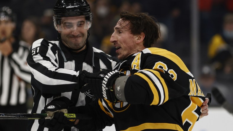 Feb 8, 2022; Boston, Massachusetts, USA; Boston Bruins left wing Brad Marchand (63) is held back by linesman Andrew Smith (51) after he got a penalty for attempting to injure during the third period against the Pittsburgh Penguins at TD Garden. Mandatory Credit: Winslow Townson-USA TODAY Sports