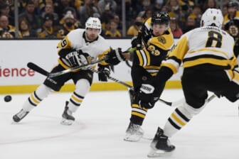 Feb 8, 2022; Boston, Massachusetts, USA; Boston Bruins left wing Brad Marchand (63) lets go with a shot between Pittsburgh Penguins defenseman Brian Dumoulin (8) and center Dominik Simon (49) during the third period at TD Garden. Mandatory Credit: Winslow Townson-USA TODAY Sports