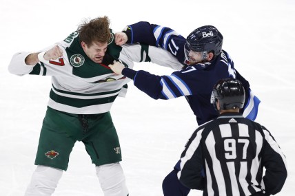 Feb 8, 2022; Winnipeg, Manitoba, CAN; Linesman Kory Nagy (97) watch as Minnesota Wild left wing Marcus Foligno (17) and Winnipeg Jets center Adam Lowry (17) fight in the third period at Canada Life Centre. Mandatory Credit: James Carey Lauder-USA TODAY Sports