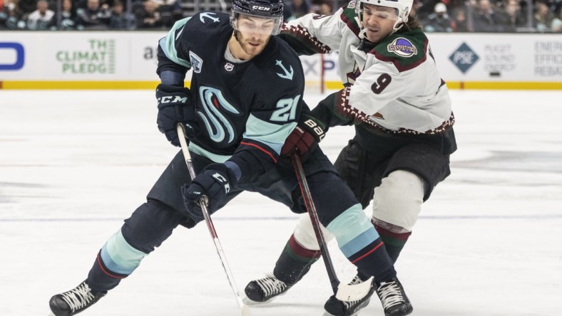 Feb 9, 2022; Seattle, Washington, USA; Seattle Kraken center Alex Wennberg (21) and Arizona Coyotes right wing Clayton Keller (9) battle for a puck during the third period at Climate Pledge Arena. Mandatory Credit: Stephen Brashear-USA TODAY Sports