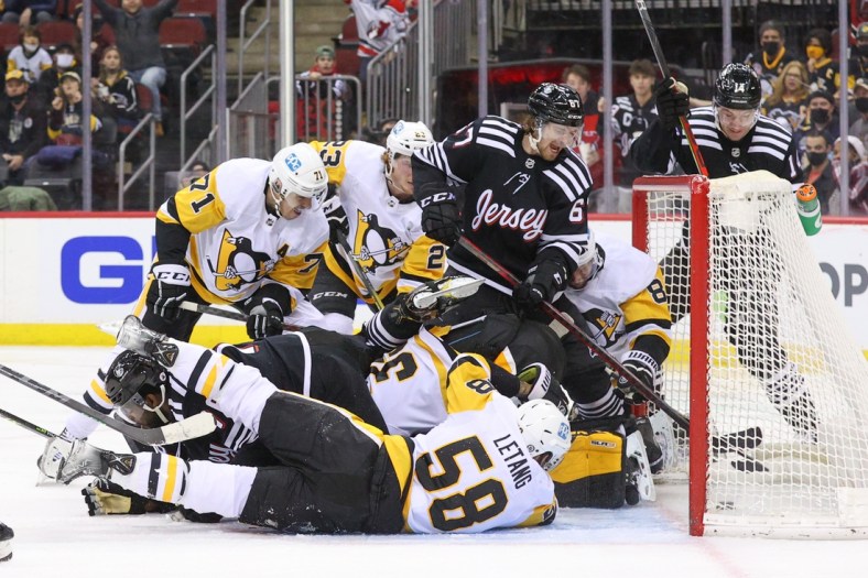 Feb 13, 2022; Newark, New Jersey, USA; Players from the New Jersey Devils and the Pittsburgh Penguins crash the net as the puck goes in during the second period at Prudential Center. The goal was disallowed. Mandatory Credit: Ed Mulholland-USA TODAY Sports