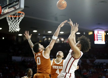 Feb 15, 2022; Norman, Oklahoma, USA;  Oklahoma Sooners forward Jalen Hill (right) shoots the ball against Texas Longhorns forward Timmy Allen (0) and forward Dylan Disu (4) in the first half at the Lloyd Noble Center. Mandatory Credit: Sarah Phipps/The Oklahoman via USA TODAY NETWORK