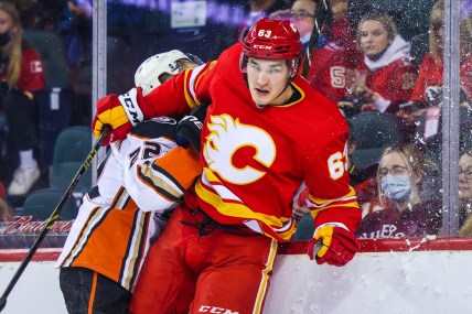 Feb 16, 2022; Calgary, Alberta, CAN; Calgary Flames center Adam Ruzicka (63) checks into the boards Anaheim Ducks defenseman Kevin Shattenkirk (22) during the first period at Scotiabank Saddledome. Mandatory Credit: Sergei Belski-USA TODAY Sports