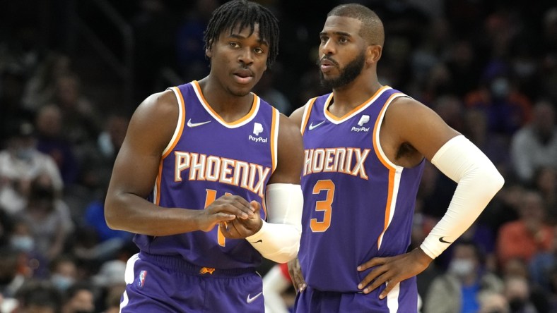 Feb 16, 2022; Phoenix, Arizona, USA; Phoenix Suns guard Aaron Holiday (4) and guard Chris Paul (3) talk during a time-out against the Houston Rockets at Footprint Center. Mandatory Credit: Rick Scuteri-USA TODAY Sports