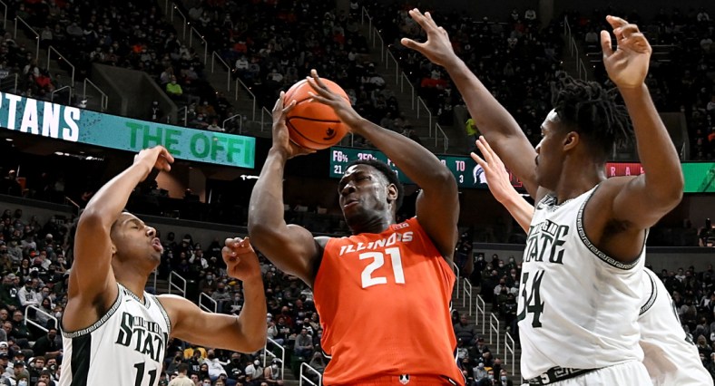 Feb 19, 2022; East Lansing, Michigan, USA; Illinois Fighting Illini center Kofi Cockburn (21) grabs a rebound in the first half against Michigan State Spartans guard A.J. Hoggard (11) and forward Julius Marble II (34) at Jack Breslin Student Events Center. Mandatory Credit: Dale Young-USA TODAY Sports