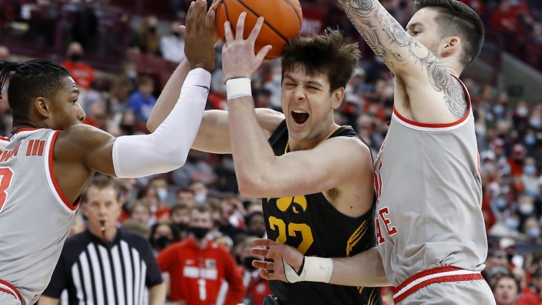 Feb 19, 2022; Columbus, Ohio, USA; Iowa Hawkeyes forward Patrick McCaffery (22) is defended by Ohio State Buckeyes guard Eugene Brown III (3) and forward Kyle Young (25) during the first half at Value City Arena. Mandatory Credit: Joseph Maiorana-USA TODAY Sports