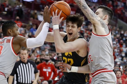 Feb 19, 2022; Columbus, Ohio, USA; Iowa Hawkeyes forward Patrick McCaffery (22) is defended by Ohio State Buckeyes guard Eugene Brown III (3) and forward Kyle Young (25) during the first half at Value City Arena. Mandatory Credit: Joseph Maiorana-USA TODAY Sports