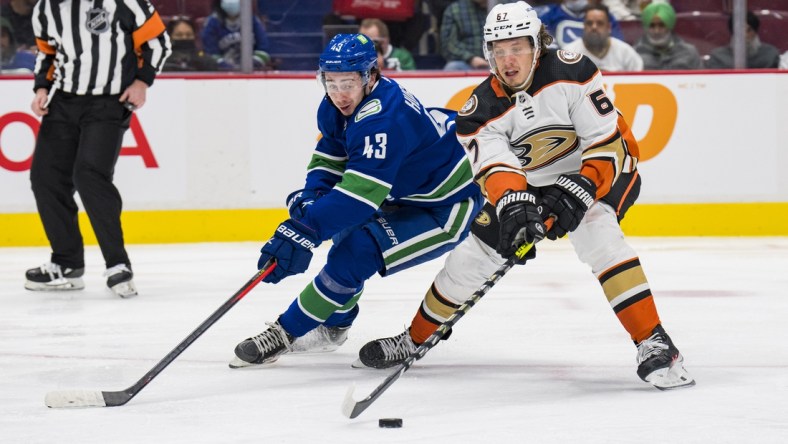 Feb 19, 2022; Vancouver, British Columbia, CAN; Vancouver Canucks defenseman Quinn Hughes (43) checks Anaheim Ducks forward Rickard Rakell (67) in the second period at Rogers Arena. Mandatory Credit: Bob Frid-USA TODAY Sports