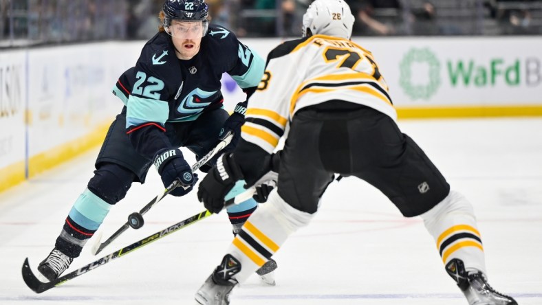 Feb 24, 2022; Seattle, Washington, USA; Seattle Kraken center Mason Appleton (22) advances the puck while being defended by Boston Bruins defenseman Derek Forbort (28) during the first period at Climate Pledge Arena. Mandatory Credit: Steven Bisig-USA TODAY Sports