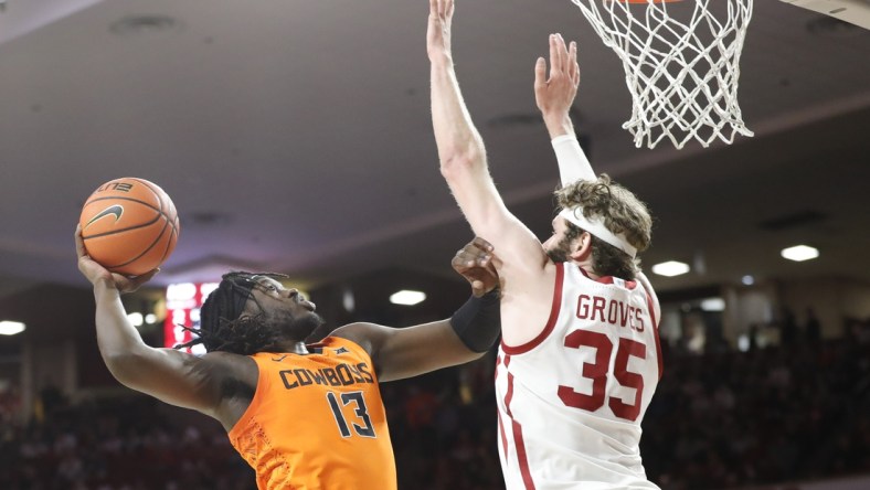 Feb 26, 2022; Norman, Oklahoma, USA; Oklahoma State Cowboys guard Isaac Likekele (13) goes to the basket as Oklahoma Sooners forward Tanner Groves (35) defends during the first half at Lloyd Noble Center. Mandatory Credit: Alonzo Adams-USA TODAY Sports