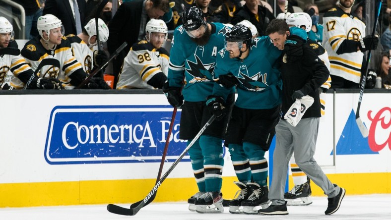 Feb 26, 2022; San Jose, California, USA; San Jose Sharks defenseman Mario Ferraro (38) is helped off the ice by defenseman Brent Burns (88) after suffering an apparent injury during the second period in the game against the Boston Bruins at SAP Center at San Jose. Mandatory Credit: John Hefti-USA TODAY Sports